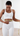 Person wearing a white sports bra and leggings measuring themselves with a tape measure.